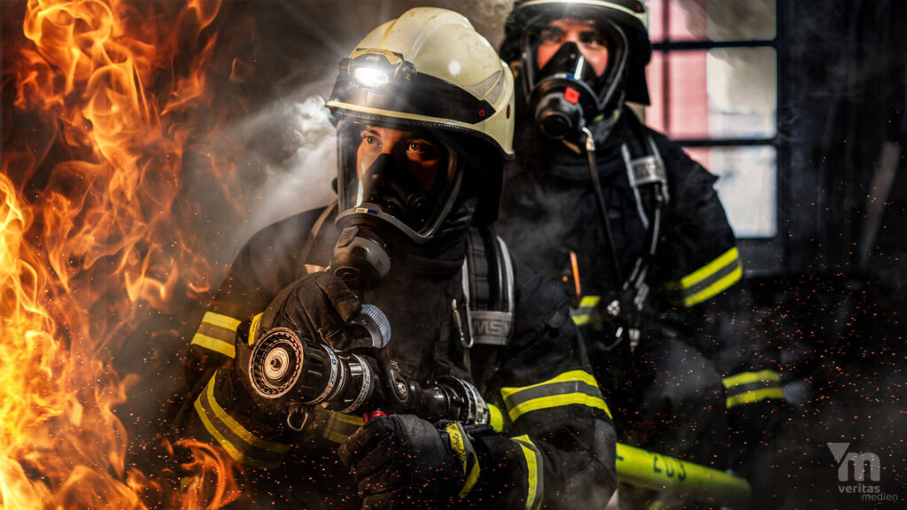Zwei Feuerwehrleute unter Atemschutz mit Strahlrohr im Innenangriff